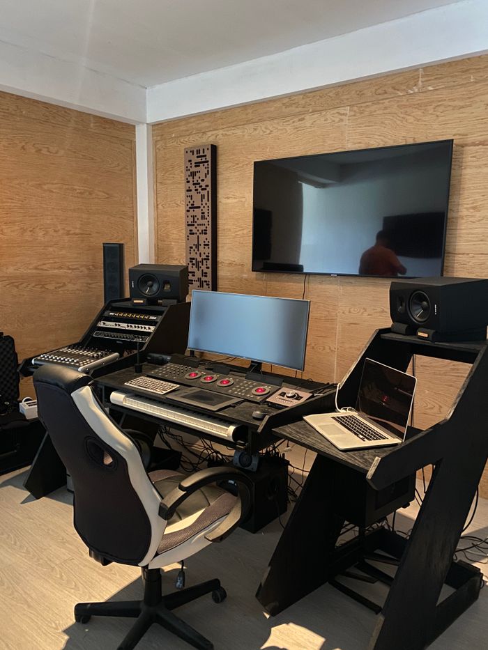 gallery-2 A modern recording studio with audio equipment, multiple screens, and ergonomic chair.