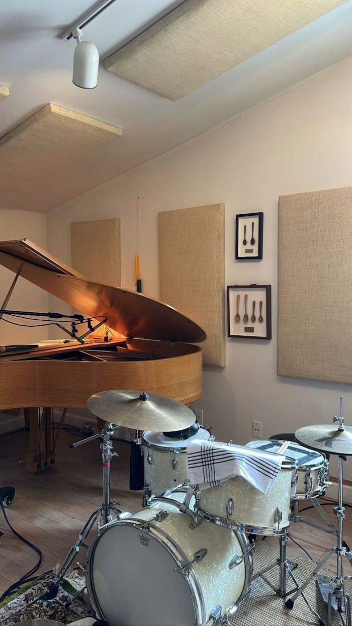 services-01 A cozy music studio featuring a grand piano and drum set, perfect for musicians.
