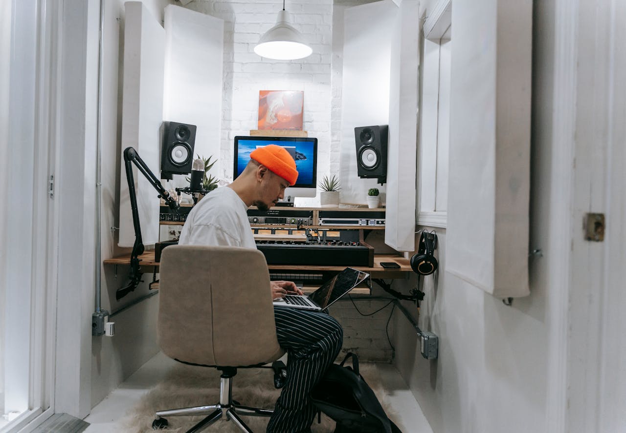 An adult male focuses on music production in a sleek, white recording studio setting.